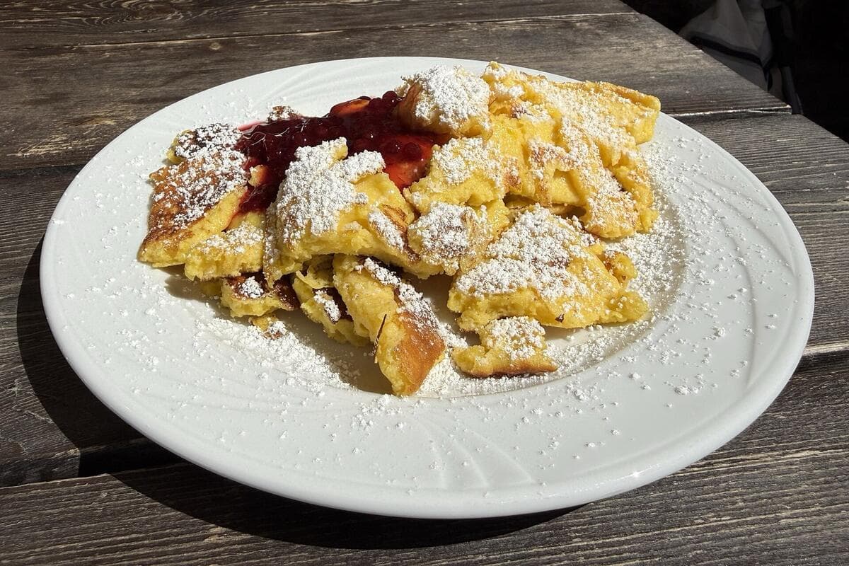 Kaiserschmarrn with berry compote on a wooden hut table
