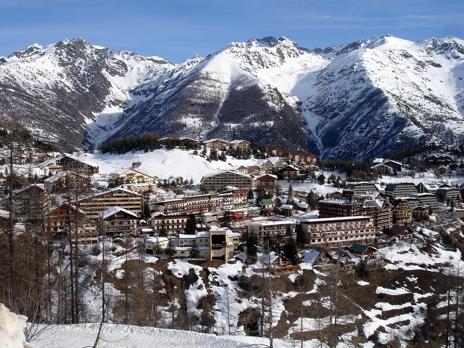 Auron's chalets and hotels on their snowy plateau, below steep, snow-covered peaks