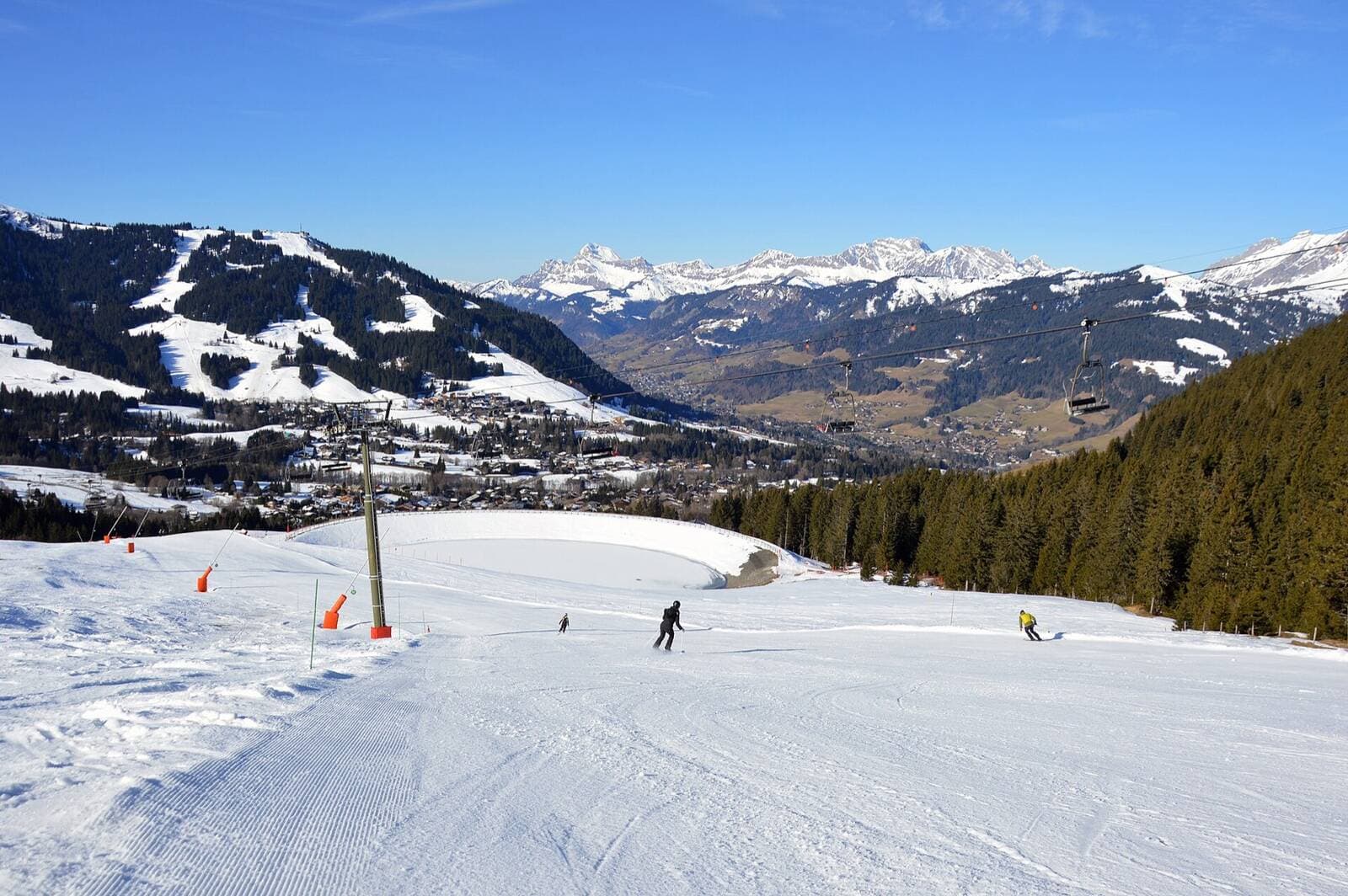 A wide sunny groomed piste above Megève with the Aravis range behind